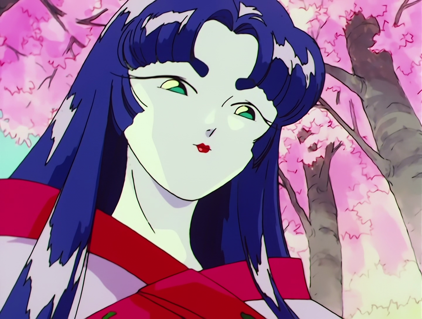 Leshy, a Cardian from Sailor Moon episode 51. In closeup, she has a pale white face and long dark blue hair. She looks very human and specifically has traditional Japanese dress and makeup.